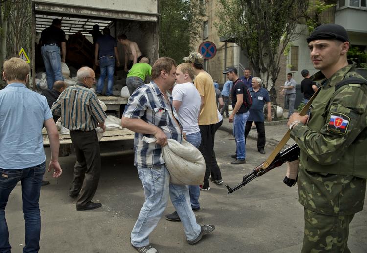 URO. Overvåget af et medlem af en russermilits i Donetsk bærer støtter sandsække til en vejspærring ud for byens lufthavn. 