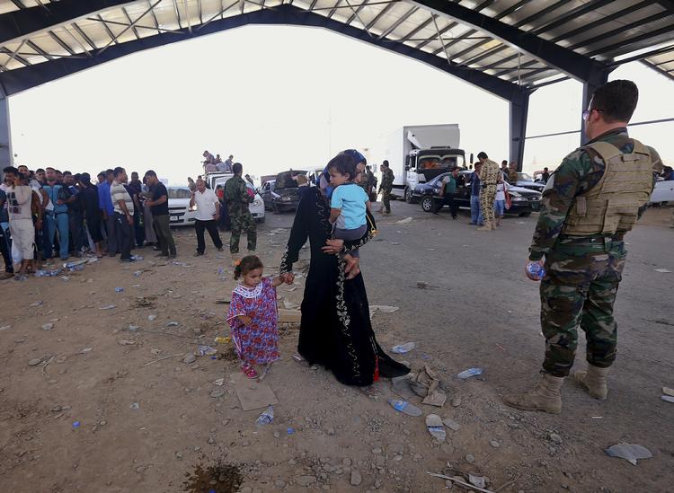 FLUGT. Beboere fra Mosul ved en af kontrolposterne ind til de kurdiske områder, hvor en kurdisk betjent holder øje med de nyankomne. 