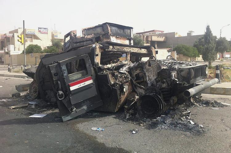 NEDKÆMPET. Pansret bil fra den irakiske hær står udbrændt tilbage på gade i Mosul. Den sunnimuslimske Isis-milits fortsætter sin fremmarch mod Bagdad, hvor den har svoret at slå til mod den shia-dominerede regering. 
