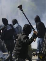En demonstrant bruger en stenslynge mod politiet. 