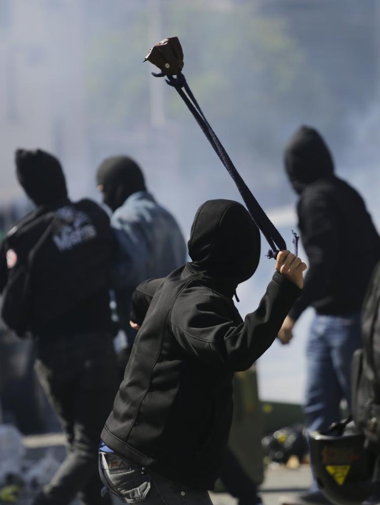 En demonstrant bruger en stenslynge mod politiet. 