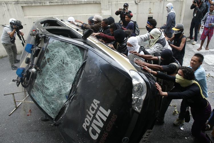 I flere brasilianske byer var demonstranterne på gaden. Her væltes en politibil i Belo Horizonte. 