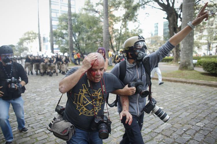 En pressefotograf fra billedbureauet Reuters er blev ramt af en sten og hjælpes i sikkerhed af en kollega. 