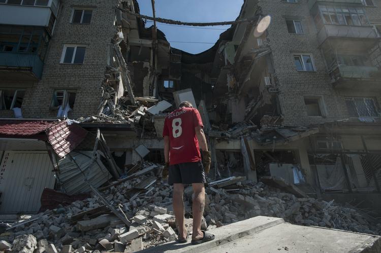 KAMPE. En mand ser på en boligblok i Mykolajivka, der er blevet ramt under kampe mellem russiske militser og det ukrainske militær. 