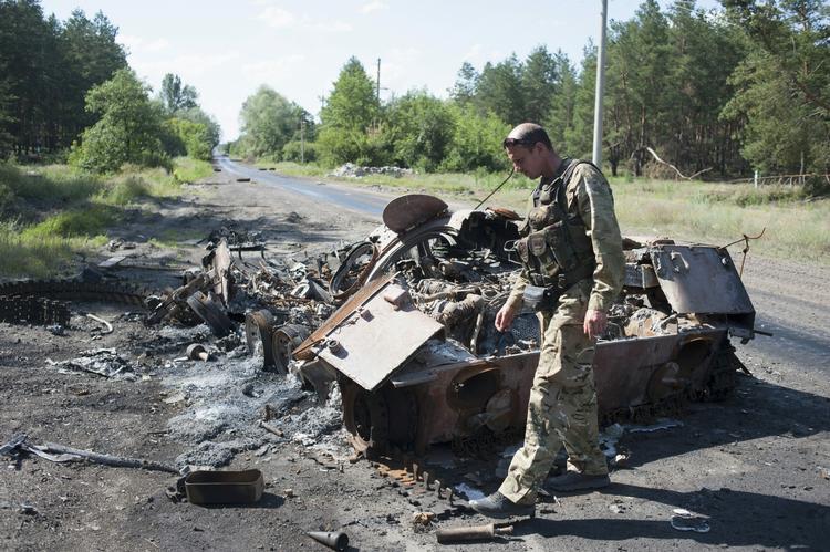ØDELAGT. Ukrainsk soldat ved de udbrændte rester af en ødelagt pansret mandskabsvogn, der blev benyttet af en russermilits under flugten fra Slavjansk. 