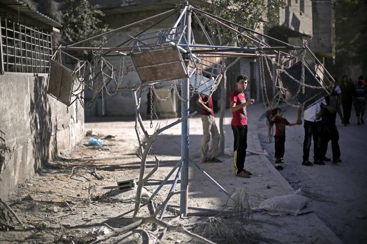 Granatregn. Palæstinensisk dreng ved et ødelagt gyngestativ på Gaza-striben i går efter et israelsk bombeangreb. 