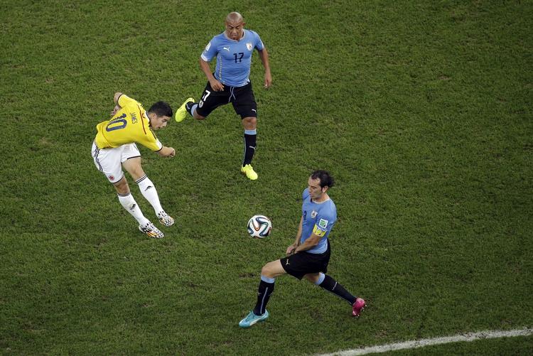 Klassekasse. James Rodriguez slog under VM sit navn fast med seks scoringer. Her har han ramt bolden lige i røven og sender Colombia foran 1-0 mod Uruguay. 