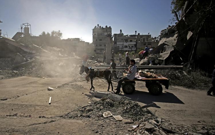 spøgelsesby. En palæstinenser trækker et æsel foran sig forbi et område, der er smadret efter et af mange israelske luftangreb. I øjeblikket er der ramadan, og normalt er folk ude i gaderne om aftenen for at højtideligholde den muslimske fastemåned. Men ikke nu, hvor israelske luftangreb i en uge har præget Gazastriben og kostet mindst 192 mennesker livet. 