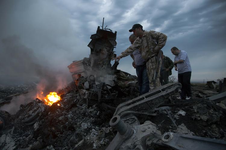 VRAGET.Soldater og civile undersøger det fuldkommen knuste fly fra Malaysia Airlines i Ukraine. 