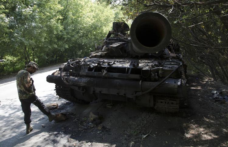 Donetsk. En prorussisk separatist står ved en udbrændt kampvogn efter en kamp med ukrainske militærstyrker. 