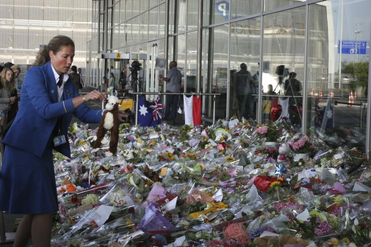 Sorg. En KLM-ansat lægger blomster og en tøjbamse foran Schiphol-lufthavn på dagen, hvor de mange hollandske ofre for flystyrtet i Ukraine flyves hjem. 