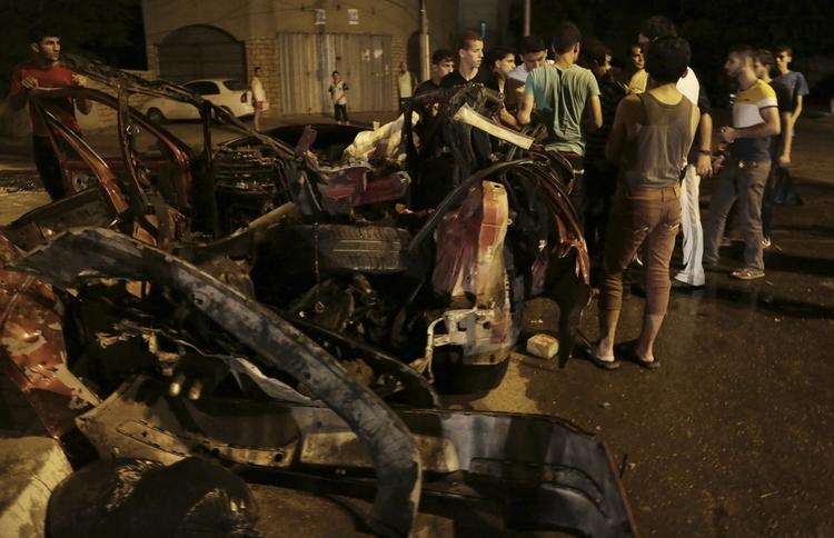 Gaza. Palæstinensere ved udbrændte bilvrag efter israelske bombeangreb. Nu tyder alt på mulighed for en kortvarig humanitær våbenhvile lørdag. 