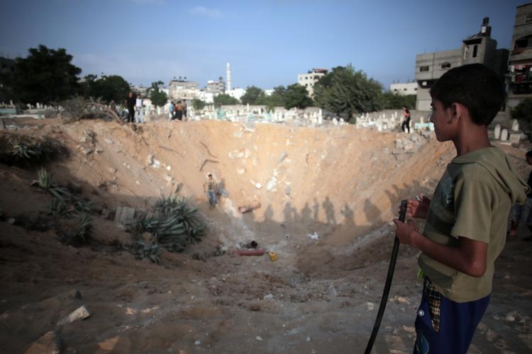Gaza-konflikt. En palæstinensisk dreng betragter en kirkegård ved en flygtningelejr i det nordlige Gaza i dag. Kirkegården er blevet bombet af israelske kampfly. 