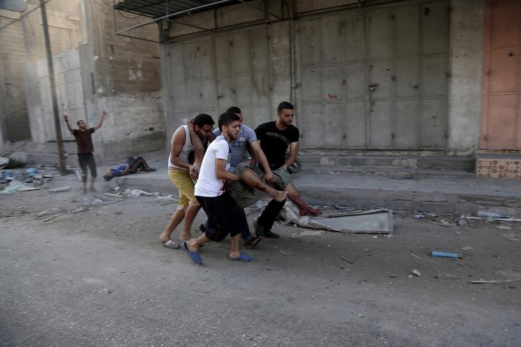 Gaza-krig. Palæstinensere bærer en såret væk, efter at israelske fly har bombet Shijaiyah-kvarteret i Gaza-by. 