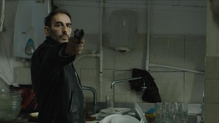 Ensom. Den ensomme lejemorder Stratos, spillet af Vangelis Mourikis, er en lille fisk i forbrydelsens element i filmen, hvor penge og ulige livsvilkår spiller en stor rolle. 