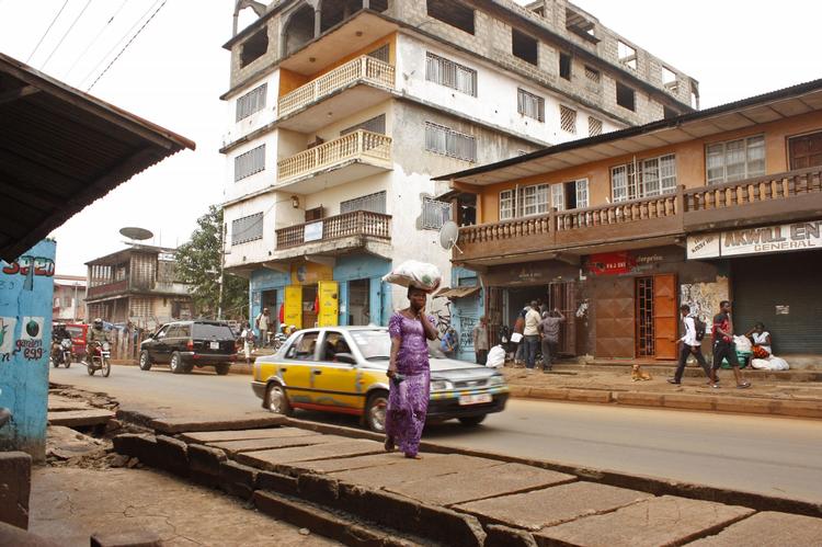 berørt. På dette billede taget for to uger siden ses en kvinde foran en klinik (med blå og gul facade) i Sierra Leones hovedstad, Freetown. Klinikken er blevet lukket, fordi en læge blev smittet med ebola, der i sit hidtil væreste udburd har kostet 672 mennesker livet i Vestafrika. 