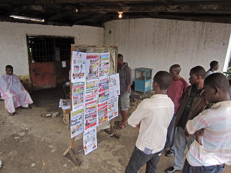Lokalaviser. Personer læser aviserne i Monrovia, Liberia, hvor overskrifterne primært handler om ebola-udbruddet i Vestafrika. En af overskrifterne er »Brænd alle lig«. 
