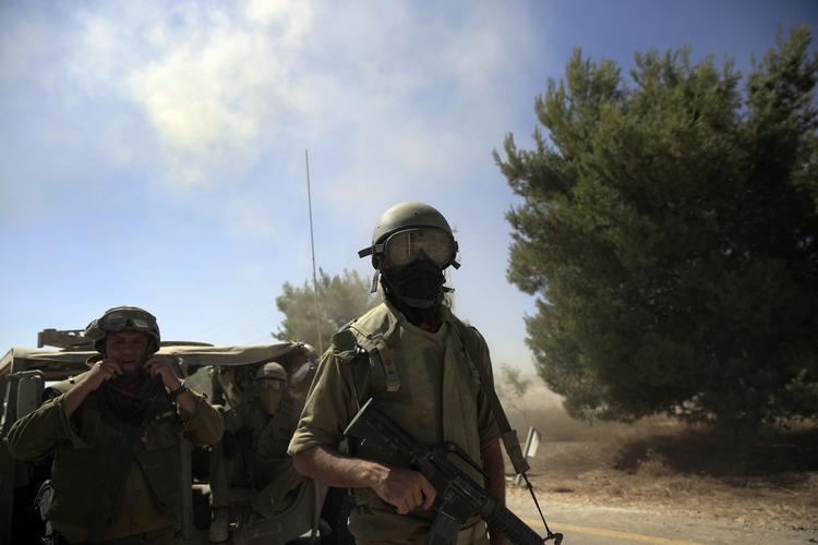Krig. Israelske soldater - med tørlæder for munden for at beskytte sig mod støv - bevæger sig bevæbnede og i tanks mod Gaza. 