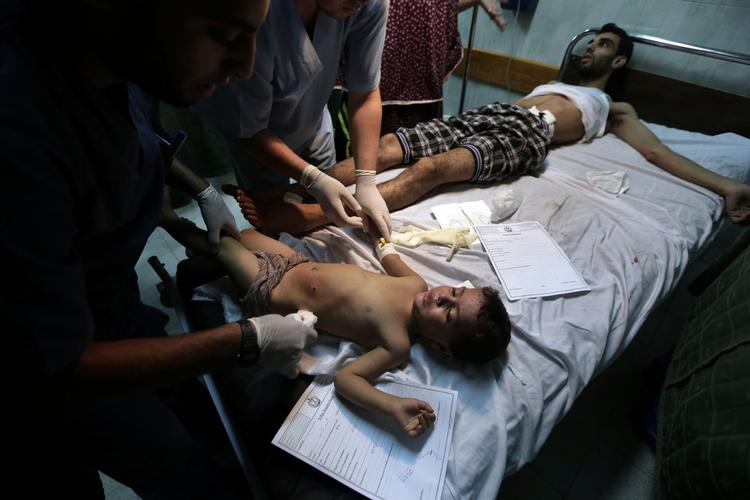 Behandling. En såret palæstinensisk dreng bliver behandlet på et hospital i Gaza. Han må dele sin seng med en voksen på hospitalets akutafdeling. 