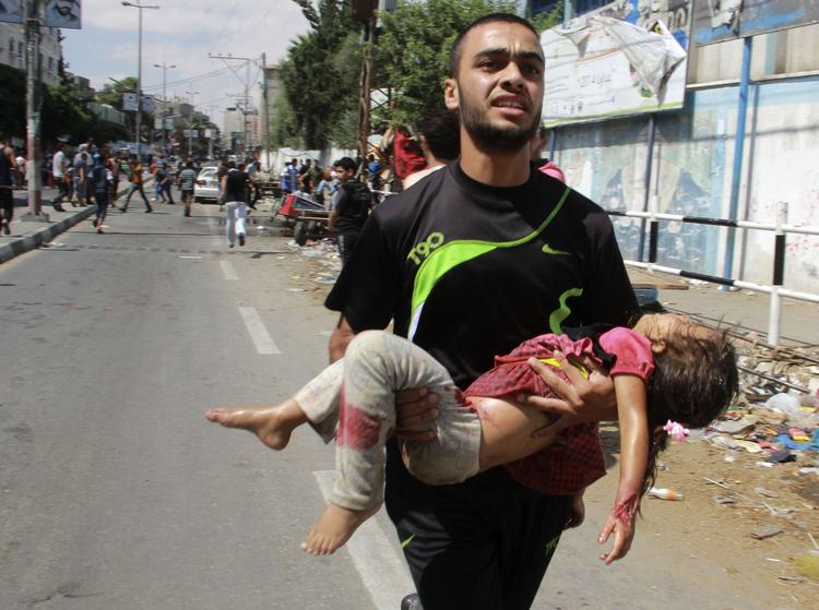 Krig. En palæstinensisk mand bærer et barn, der er blevet dræbt under et angreb ved en FN-drevet skole i Rafah i det sydlige Gaza. Mindst 10 personer blev dræbt ved angrebet. 