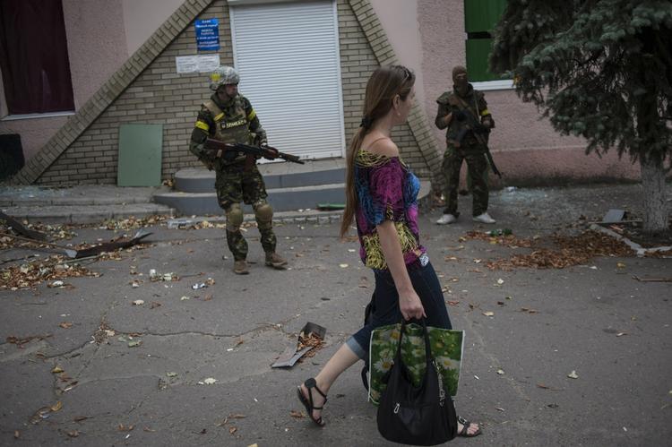 KAMP. Kvinde passerer soldater fra den ukrainske regeringshær i byen Mariinka nær Donetsk. 