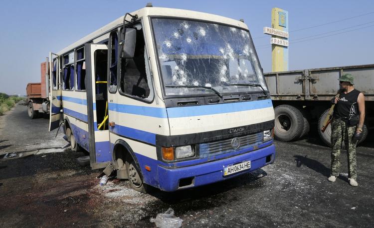 Dræbte. Prorussiske rebeller bevogter en kontrolpost nær en skudhullet bus, hvor mindst 12 militsmedlemmer, der kæmpede på ukrainsk side blev dræbt i et baghold. FN har opjusteret opgørelsen over antallet af dræbte i konflikten. 