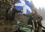VALGKAMP. Førsteminister Alex Salmond - leder af selvstændighedspartiet SNP - rækker en vælger en paraply med det skotske flag. 