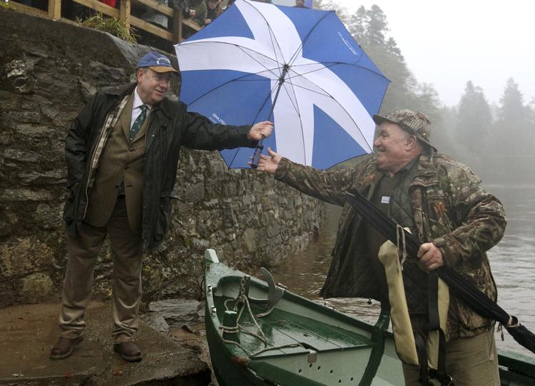 VALGKAMP. Førsteminister Alex Salmond - leder af selvstændighedspartiet SNP - rækker en vælger en paraply med det skotske flag. 