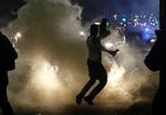 optøjer. Demonstranter løber væk fra politiets tåregas i Ferguson i Missouri, USA. Demonstranterne har været på gaden i tusindvis, siden en sort 18-årig teenager i forrige uge blev skudt af en hvid betjent. 