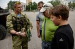 Militært. En pro-russisk oprører patruljerer i storbyen Donetsk. Han har tid til at vise en granat frem for indbyggere. 