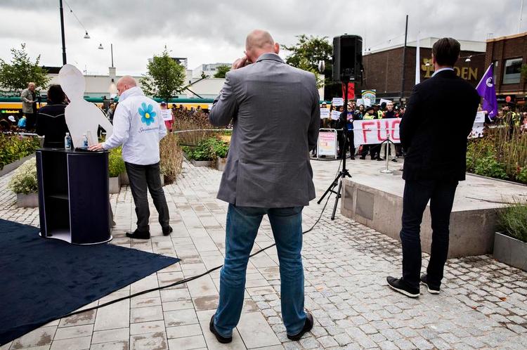 Udsat. Sverigedemokraten Björn Söder iført hvide jakke med partiets blomsterlogo er konstant overvåget af sikkerhedsvagter. Mere end 30 politifolk i uniform og i civil fulgte med, da han holdt sin tale i Norrköping. 