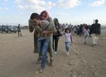 FLUGT. Syrer bærer en ældre kvinde på ryggen op mod grænsen til Tyrkiet under flugten fra Islamisk Stat. 