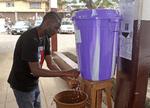 Smitte. En mand vasker sine hænder i desinfektionsvæske uden for et hospital i Freetown i  Sierra Leone. Røde Kors mener,a t der er brug for mere oplysning, hvis sygdommen skal standses. 