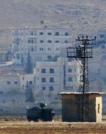 På dette foto taget fra den tyrkiske by Suruc med en kraftig telelinse ses en gruppe mænd hejse Islamisk Stats karakteristiske sorte flag i den østlige del af byen Kobani. 