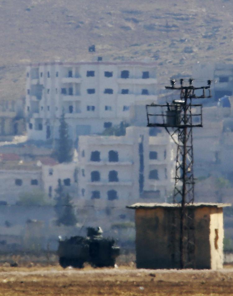 På dette foto taget fra den tyrkiske by Suruc med en kraftig telelinse ses en gruppe mænd hejse Islamisk Stats karakteristiske sorte flag i den østlige del af byen Kobani. 