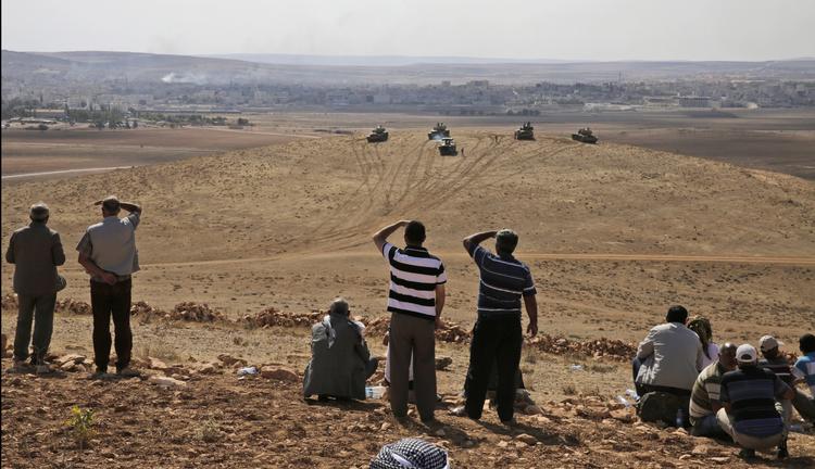 TILSKUERE. Fra den tyrkiske side af grænsen følger lokale kamphandlingerne i Kobane i sikkerhed bag tyrkiske kampvogne. 