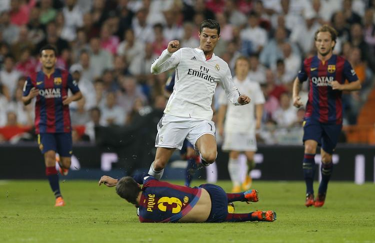 TACKLING. Real Madrid's Cristiano Ronaldo bliver her tacklet af Barceona's Gerard Pique i aftenens kamp. 