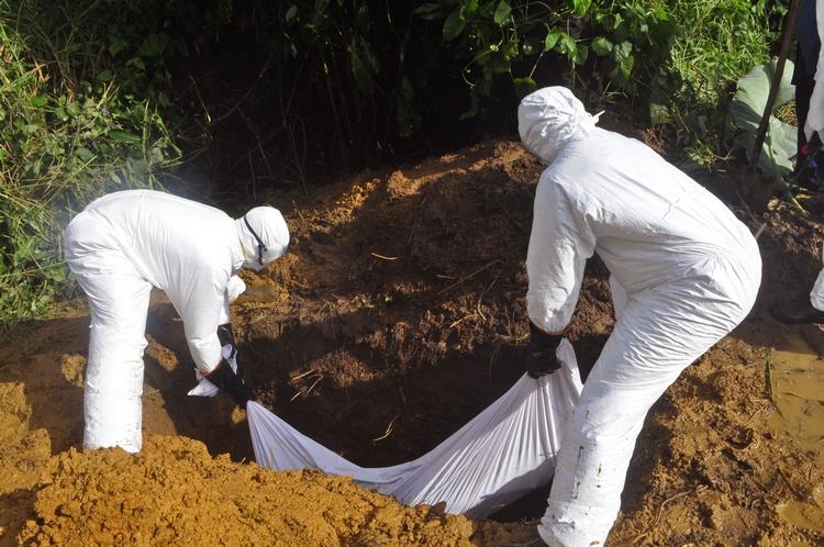 ebola. Sundhedsmedarbejdere lægger liget af en mand, der vurderse at være død som følge af ebola, i en grav i udkanten af Monrovia i Liberia. 