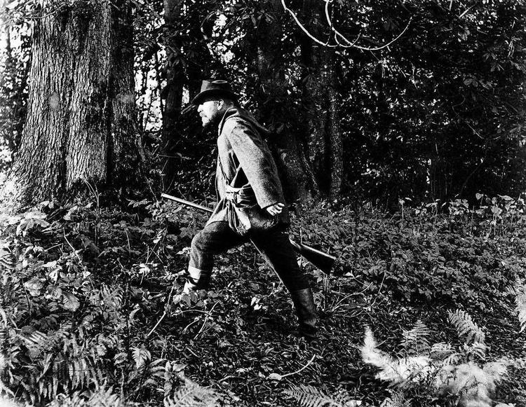 jæger. Wilhelm Dinesen skrider igennem skoven, formentlig under en jagt i 1894, året før hans død. I en årrække havde han under pseudonymet Boganis skrevet 'jagtbreve' til Politiken. 