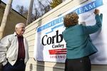 Pennsylvanias guvernør, republikaneren Tom Corbett, ser sin kone skrive sin autograf på en valgplakat ved valgstedet i staten. 