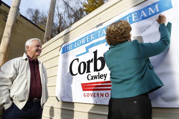 Pennsylvanias guvernør, republikaneren Tom Corbett, ser sin kone skrive sin autograf på en valgplakat ved valgstedet i staten. 