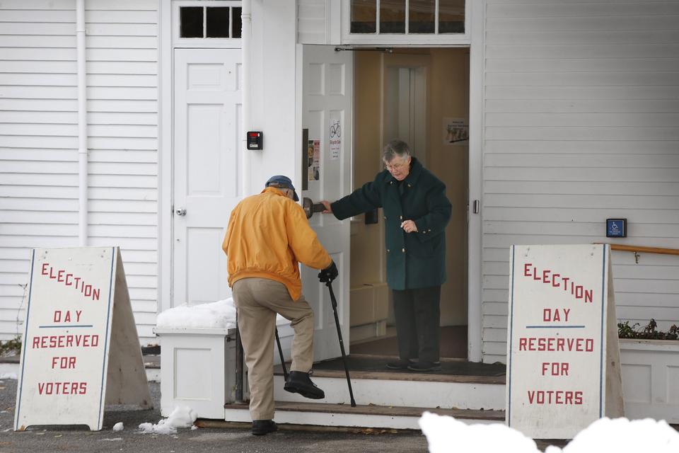 Vælgeren Elaine Davis holder døren for en anden vælger, Sidney Lindsley, ved indgangen til et valgsted i Camden, Maine. 