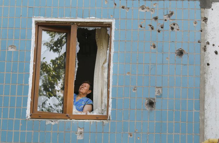 KAMPOPMRÅDE. Kvinde forsøger at reparere sig vindue i Donetsk, hvor russiskstøttede militser kæmper mod Ukraines forsvar. 