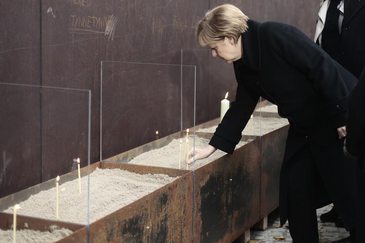 Minde. Den tyske kansler Angela Merkel tænder et lys på 25-års dagens for Berlin-murens fald. 