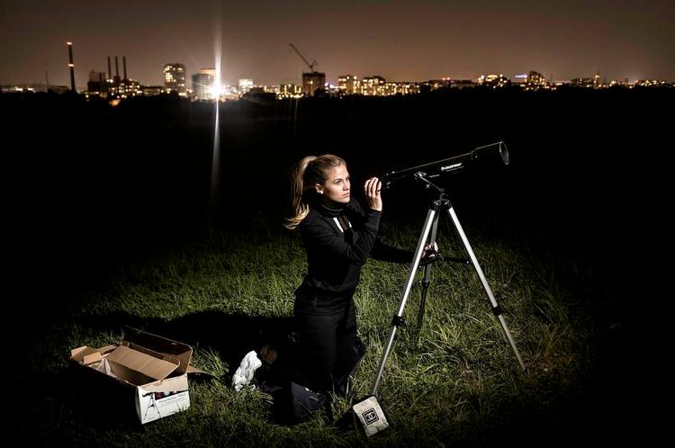 Halløj derude. Radioværten Sara Frost har investeret i et teleskop, fordi hun er fascineret af, hvor meget man kan se på himlen – selv som her omgivet af byens lys på Amager Fælled. Foto: Peter Klint 