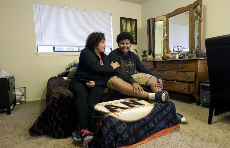 Hjemløshed. Gina Cooper og hendes 14-årige søn Dante Walton smiler i deres hjem i San Carlos i Californien. For to år siden var de hjemløse og måtte overleve med hjælp fra herberger og kirker, da Ginas løn ikke rakte til at betale huslejen. 