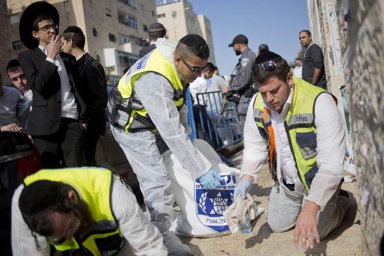 Terror. Israelske redningsarbejdere vasker blodstænk væk efter dagens angreb på en synagoge, hvor fire bedende og de to gerningsmænd blev dræbt. 