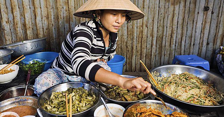 Spis. En vietnamesisk kvinde sælger hjemmelavet mad på et marked i det centrale Vietnam. 