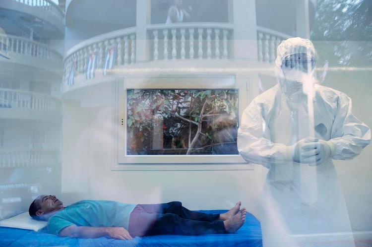 Prøve. Sygeplejerske Eduardo Brito Perez fra Cuba skal foregive, at han har symptomer på ebola. Imens ser andre cubanere til fra hotellets balkon. 