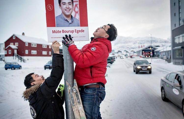 Slutspurt. Valgplakaterne er først blevet synlige i Nuuk de seneste døgn af valgkampen, fordi man er bange for, at de ellers blæser ned. Her er det en plakat for IA's ungdomsformand, der er ved blive hængt op i en lygtepæl. 